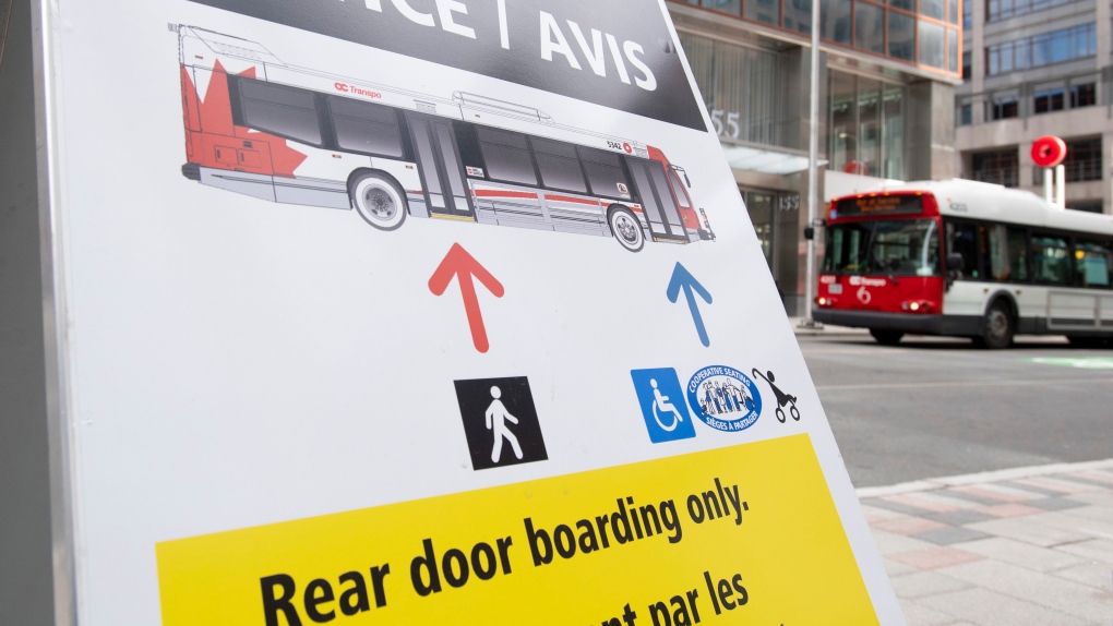 A bus passes a sign indicating users should enter the bus by the rear door as part of COVID-19 measures in Ottawa, Thursday April 16, 2020. (Adrian Wyld/THE CANADIAN PRESS)