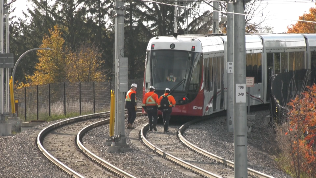 Workers with Alstom and RTG watch as an LRT car moves along the Confederation Line on Oct. 27, 2021, near the spot where a train derailed on Sept. 19. (Jeremie Charron/CTV News Ottawa)