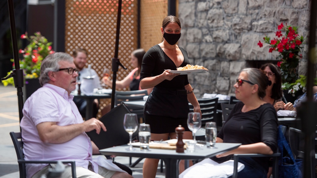 A server brings an order to patrons on a steakhouse's outdoor patio in Ottawa on the first day of Ontario's first phase of re-opening amidst the third wave of the COVID-19 pandemic, on Friday, June 11, 2021. (Justin Tang/THE CANADIAN PRESS)