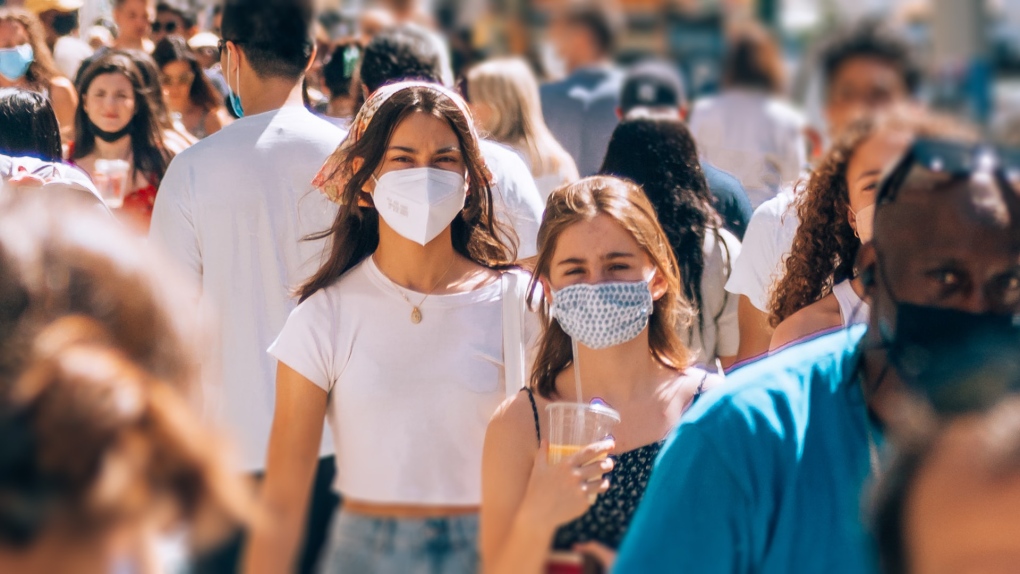 People walk down a busy street wearing masks during the COVID-19 pandemic. (Photo by Yoav Aziz on Unsplash)