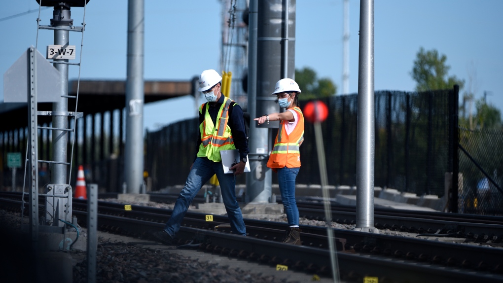 Workers wearing a hard hats from train manufacturer Alstom work among evidence markers laid on the tracks Monday, Sept. 20, 2021 after an OC Transpo O-Train derailed west of Tremblay LRT Station on Sunday in Ottawa. (Justin Tang /THE CANADIAN PRESS)