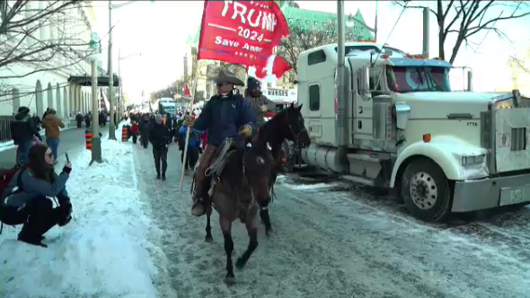 Two protesters on horseback ride along Wellington Street Saturday afternoon. 