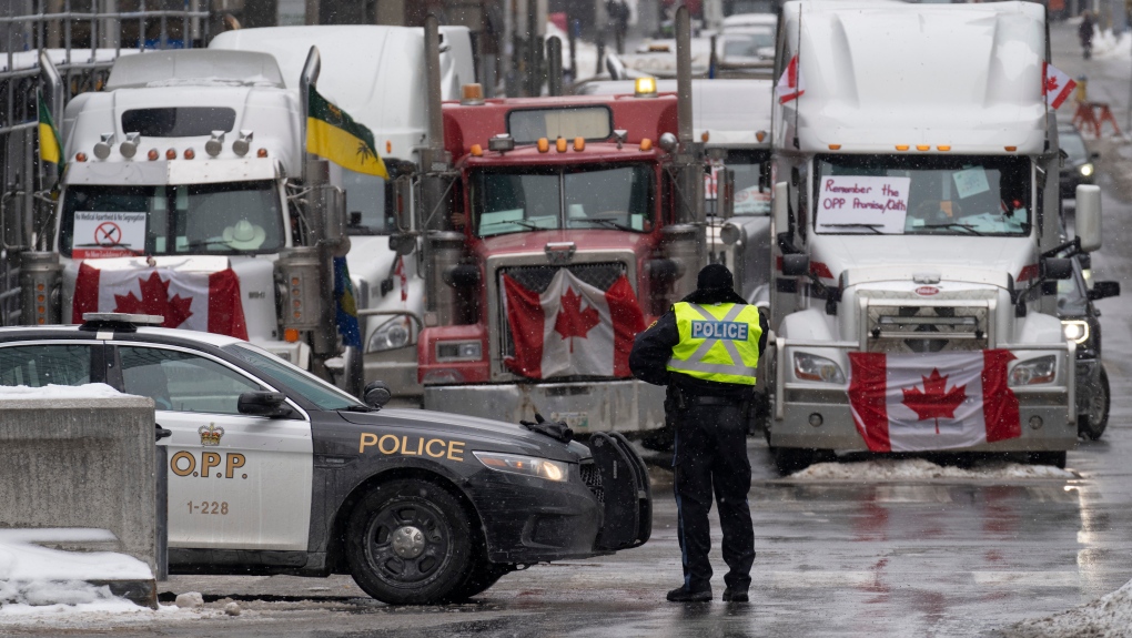 Police man a barricade in front of vehicles parked as part of the trucker protest, Tuesday, Feb. 8, 2022 in Ottawa’s downtown core. (Adrian Wyld/THE CANADIAN PRESS)