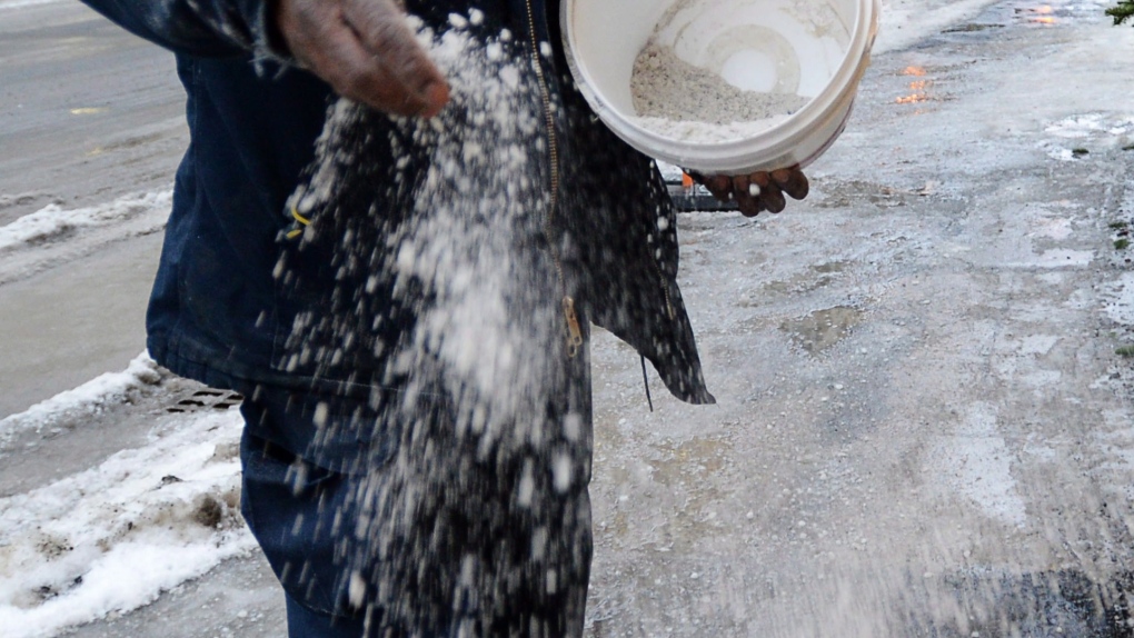 A man spreads salt on a sidewalk in downtown Ottawa in this file photo. (Sean Kilpatrick/THE CANADIAN PRESS)