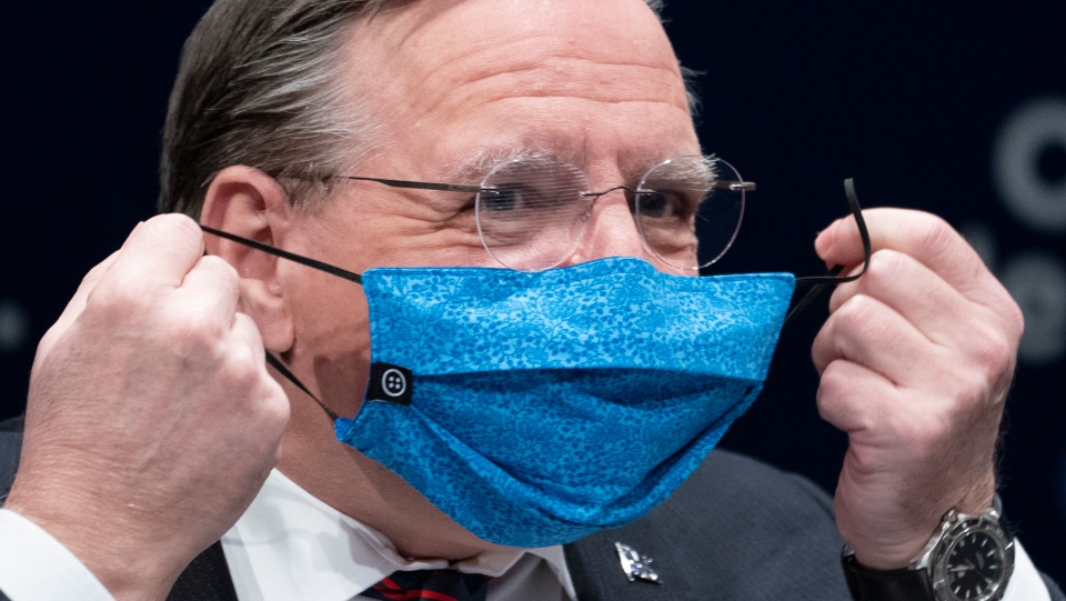 Francois Legault removes his protective mask